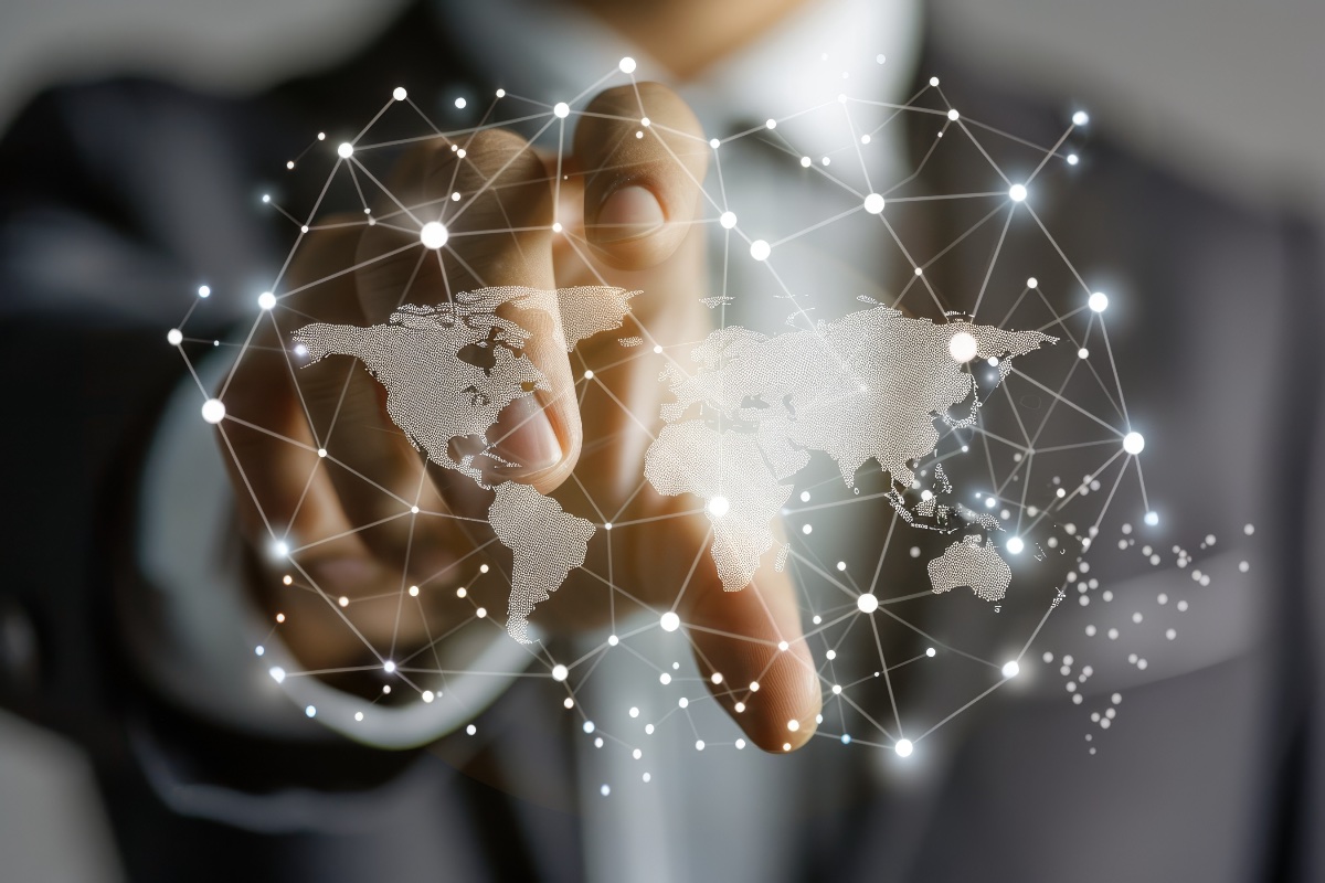 Hand mit leuchtender Weltkarte und vernetzten Knotenpunkten — Symbol für internationale Verbindungen